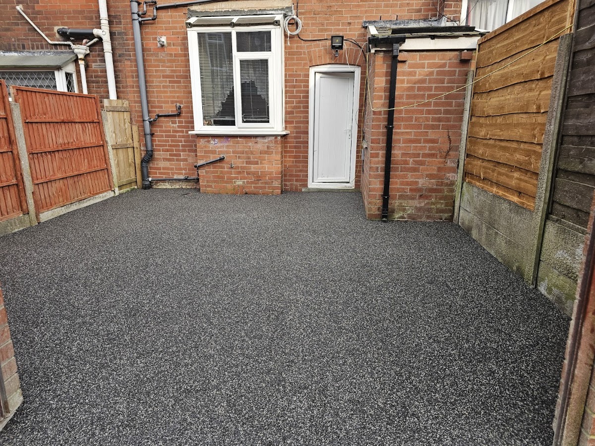 Resin bound surface in a charcoal and silver blend, laid across a rear yard