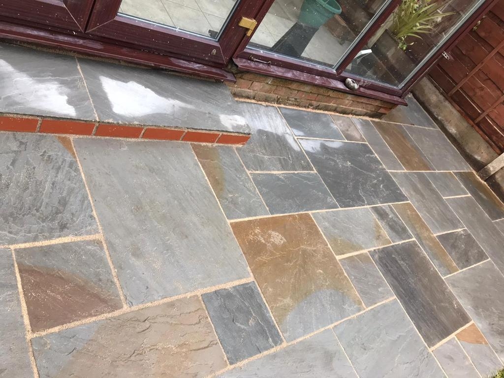 Riven Indian sandstone patio in mixed grey and buff, with brick edging