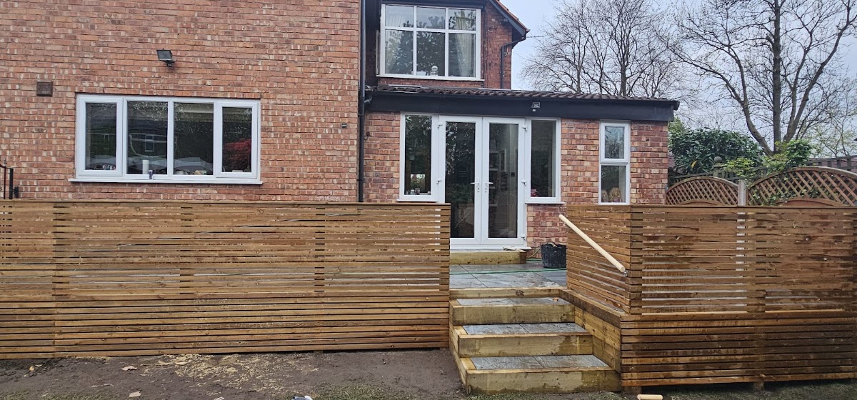 Rear garden with slatted timber screen fencing, sleeper steps and a flagged landing